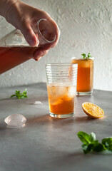 Summer iced tea with lemon and ice in a misted glass with droplets on a gray background