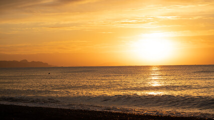 Amazing sunrise over the tropical beach. Yellow sun over sea. Orange colors waves. Nature background. Beautiful serene scene. Morning. Sunlight reflect on water surface