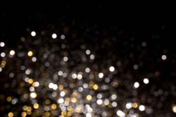 Golden and silver blurred bokeh lights on black background. Glitter sparkle stars for celebrate....
