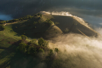 Fototapeta na wymiar Aerial view of mountain landscape with morning fog, at the forest edge, in Romania