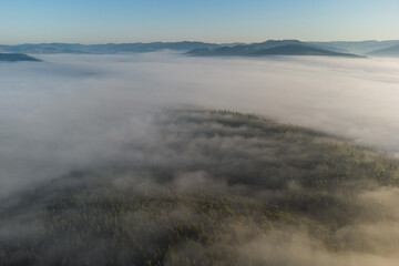Aerial view of mountain landscape with morning fog, at the forest edge, in Romania
