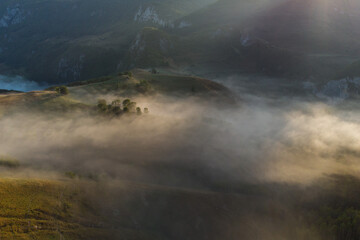 Fototapeta na wymiar Aerial view of mountain landscape with morning fog, at the forest edge, in Romania