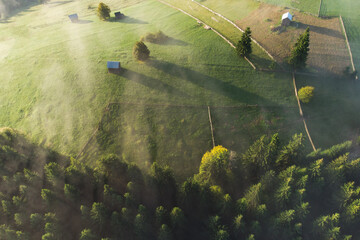 Aerial view of mountain landscape with morning fog, at the forest edge, in Romania