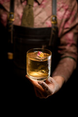 beautiful flower petal decorating cold cocktail in glass gently held by male hand