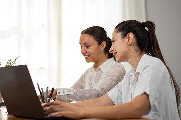 Mujeres de negocio observan su laptop mientras trabajan en su oficina.