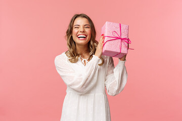 Holidays, celebration and women concept. Portrait of happy charismatic blond girl shaking gift box...