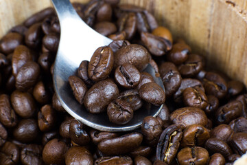 Roasted coffee beans in the wooden pot. Close up, macro photo.
