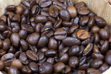 Roasted coffee beans in the wooden pot. Close up, macro photo.