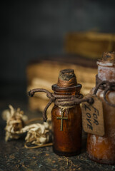 Magic potions in bottles, ancient books and witchery herbs on wooden background, Halloween theme