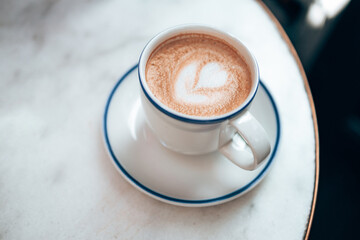 Glass cup of hot aromatic coffee cappuccino on white marble table in street cafe in the morning