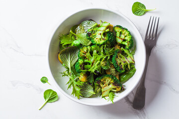 Green salad with grilled broccoli and olives in white bowl. Vegan food, detox, healthy food concept