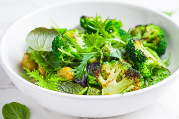 Green salad with grilled broccoli and olives in white bowl. Vegan food, detox, healthy food concept