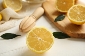 Wooden citrus reamer and fresh lemons on white table