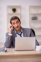 Young male employee unhappy with excessive work in the office