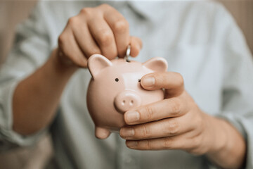 Woman hands hold a pink piggy bank and coin puts. Saving money or savings, investment concept