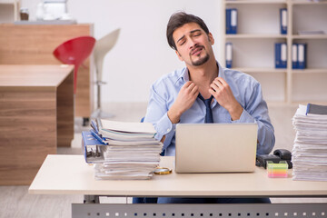 Young male employee and too much work in the office