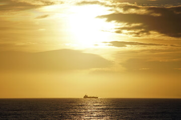 Naklejka na ściany i meble Morning in the open ocean. Sunrise and the silhouette of a ship on the horizon. Atlantic.