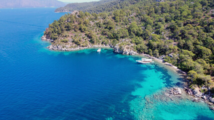Aerial drone photo of pleasure yacht anchored in crystal clear bay and turquoise beach. uninhabited island in mediterranean sea. Place for swimming in sea while tourist boat trip