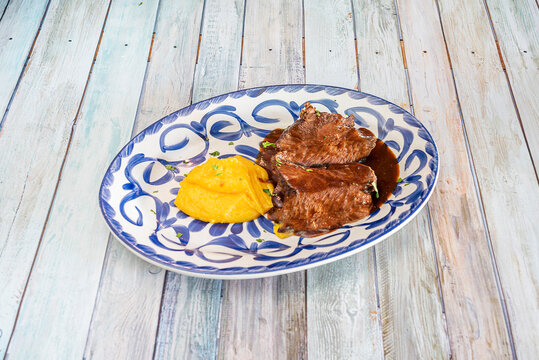 Delicious Spanish Recipe For Beef Cheek Stewed In Sauce And Sweet Potato Puree With Parsley On A Blue Porcelain Plate From Talavera