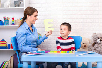 Toddler boy in child occupational therapy session doing sensory playful exercises with her therapist.