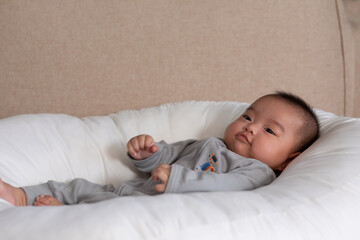 Adorable Asian baby girl lying on bed looking at camera.Cute little baby smiling and happiness relaxing in bed.Portrait of asian baby newborn in bedroom