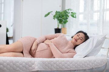 Happy Beautiful Pregnant Asian Woman lying on bed smile and sleep with big belly so comfortable and...