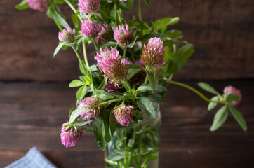 red clover in a jar on wooden table