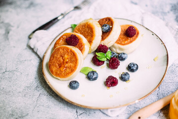 cheesecakes with berries and sauce on a gray background