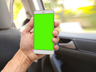 Man riding on back seat of car and holding smartphone with green chromakey screen