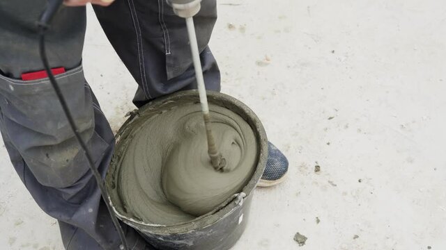 young male bricklayer builder kneads concrete, for laying aerated concrete blocks, using a construction mixer on a construction site. Free space for text. Copy space