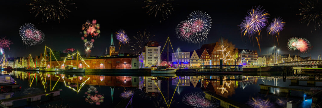 Fireworks on the river Trave.  Panorama view of festive lighting with firework romantic atmosphere on the river Trave in the Hanseatic city of L&uuml;beck at night. Fairy lights on the masts of the ships.