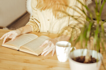 woman in yellow shirt with cup of coffee and book on wooden table