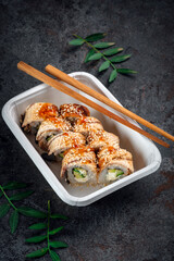 Unagi Philadelphia roll set with cream cheese, cucumber and avocado in a delivery box with chopsticks. Japanese dish with eel fish