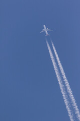 twin engine aeroplane in the clear blue sky leaving vapor trails behind