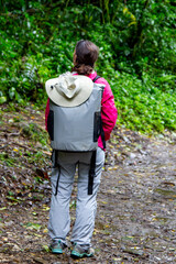 Woman in pink jacket and grey cooler bag walking in the cloud forest of Costa Rica