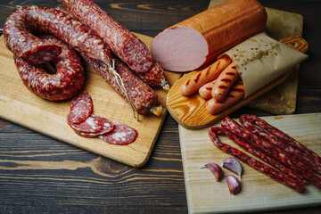 Various types of meat and sausages on wooden table, served on board, closeup. Top view.
