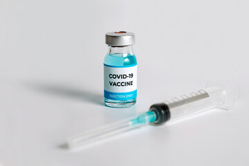 Close up of Covid-19 vaccine vials and syringe on white background. Hand takes one bottle of vaccine. Medical vaccination concept banner.