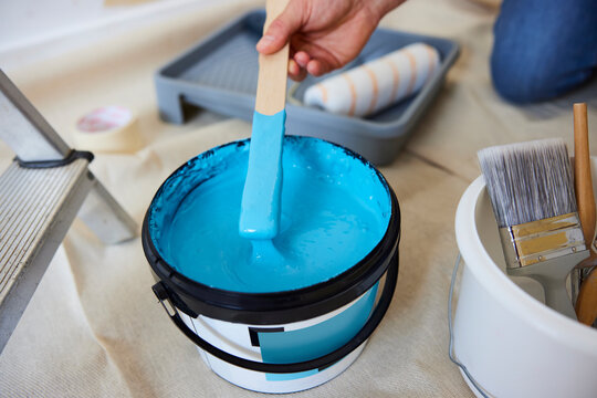 Close Up Of Man Stirring Paint Before Decorating Room At Home