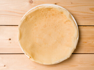 Round pancake in a white plate on a wooden background. View from above
