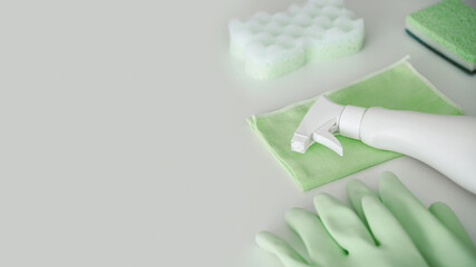 Green protective gloves, rag, sponge and sprayer with chemical detergent on white background. Housework and professional eco cleaning service supplies.