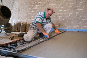 Construction worker smoothing concrete above the radiant underfloor system.