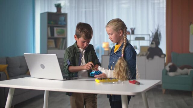 children repair a mini quadcopter with tools and then give each other five, girl with plaster cast on her arm helps her younger brother