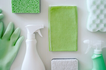 Green protective gloves, sponges, rag, brush, spray cleaner bottle with chemical detergent on white...
