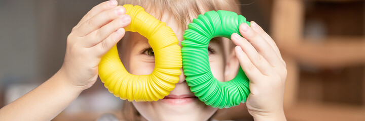 anti stress sensory pop tube plastic toy in kid's hands. a little happy child boy plays with a...