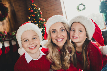 Photo of mother and children boy and girl smile good mood smile friends wear santa claus hat indoors inside house home