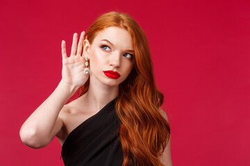 Romance, elegance, beauty and women concept. Close-up portrait of serious-looking intrigued nosy redhead woman trying to overhear conversation, eavesdropping on party, wear black dress