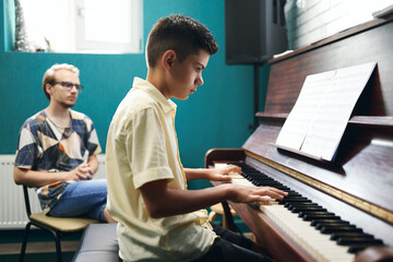 Piano teacher with a student playing the piano at lesson
