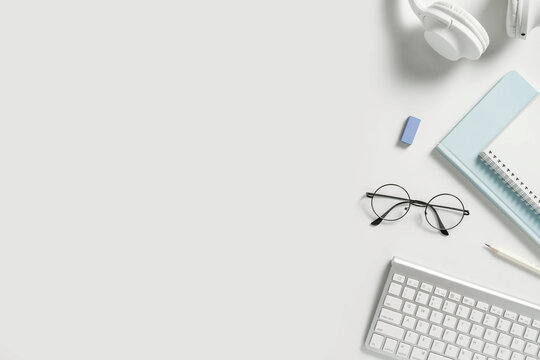 Online learning education, freelance and office work minimalistic flat lay with copy space. Stationery, headphones, notebook, pencil, glasses on white background.