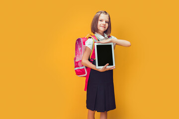 Cute Schoolgirl preparing to go to school with backpack showing the tablet. Back to school concept 