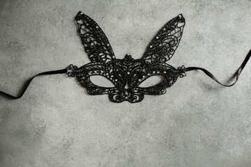 Black sexy lace face mask with bunny ears and rhinestones for Halloween party on grey background, top view